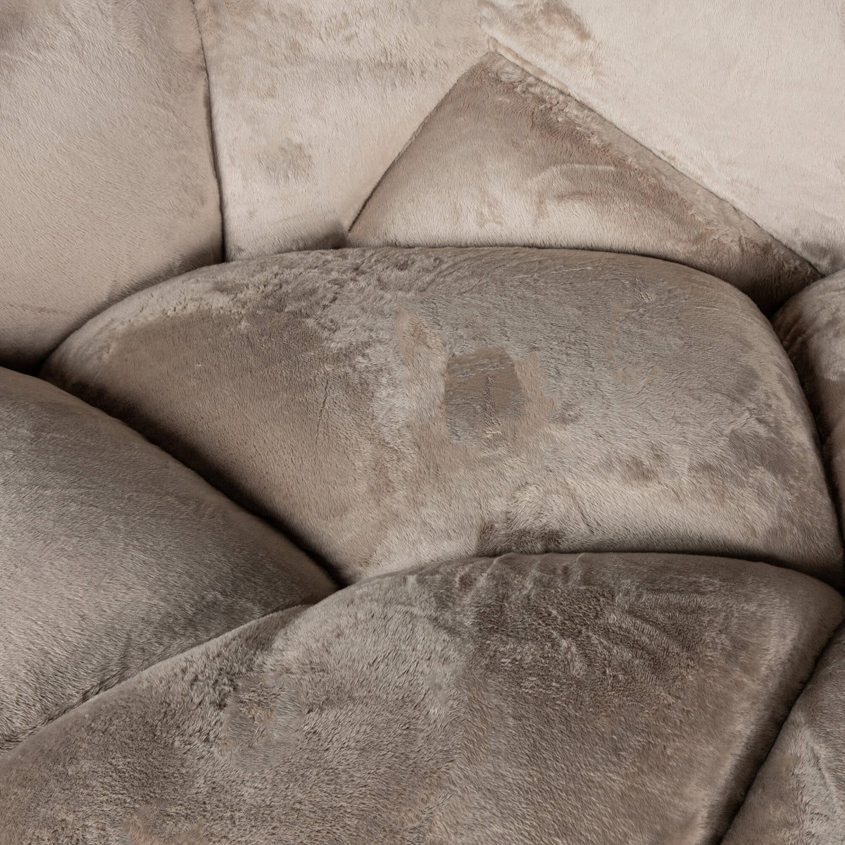 Close-up van de rijke, zachte textuur van de beige Lush-stof en het verfijnde gecapitonneerde patroon.