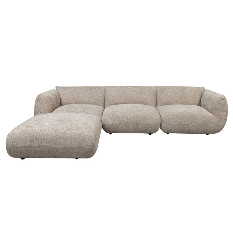 Vooraanzicht van de vrijstaande 4-zits loungebank in kleur latte met afgeronde lijnen, comfortabele 38 kg/m³ schuimvulling en aangesloten ottoman aan de linkerzijde.