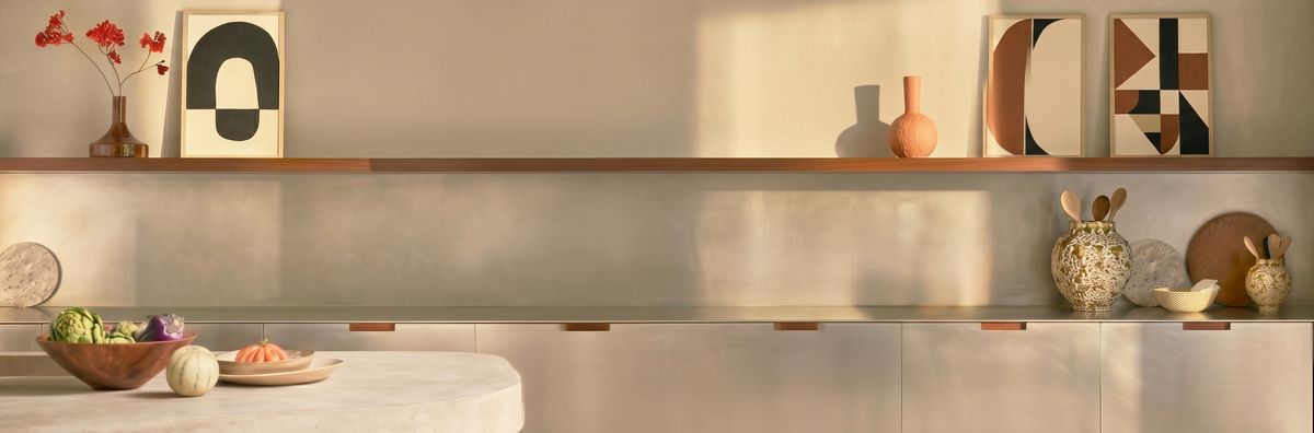 een sfeervolle, brede banner-afbeelding voor de contactpagina, met een verfijnde, strakke keuken in Modern Organic stijl, voorzien van een marmeren werkblad, een decoratieve houten wandplank met kunst en keramiek, en warm invallend zonlicht voor een gastvrije uitstraling. Dient als banner pagina contact.